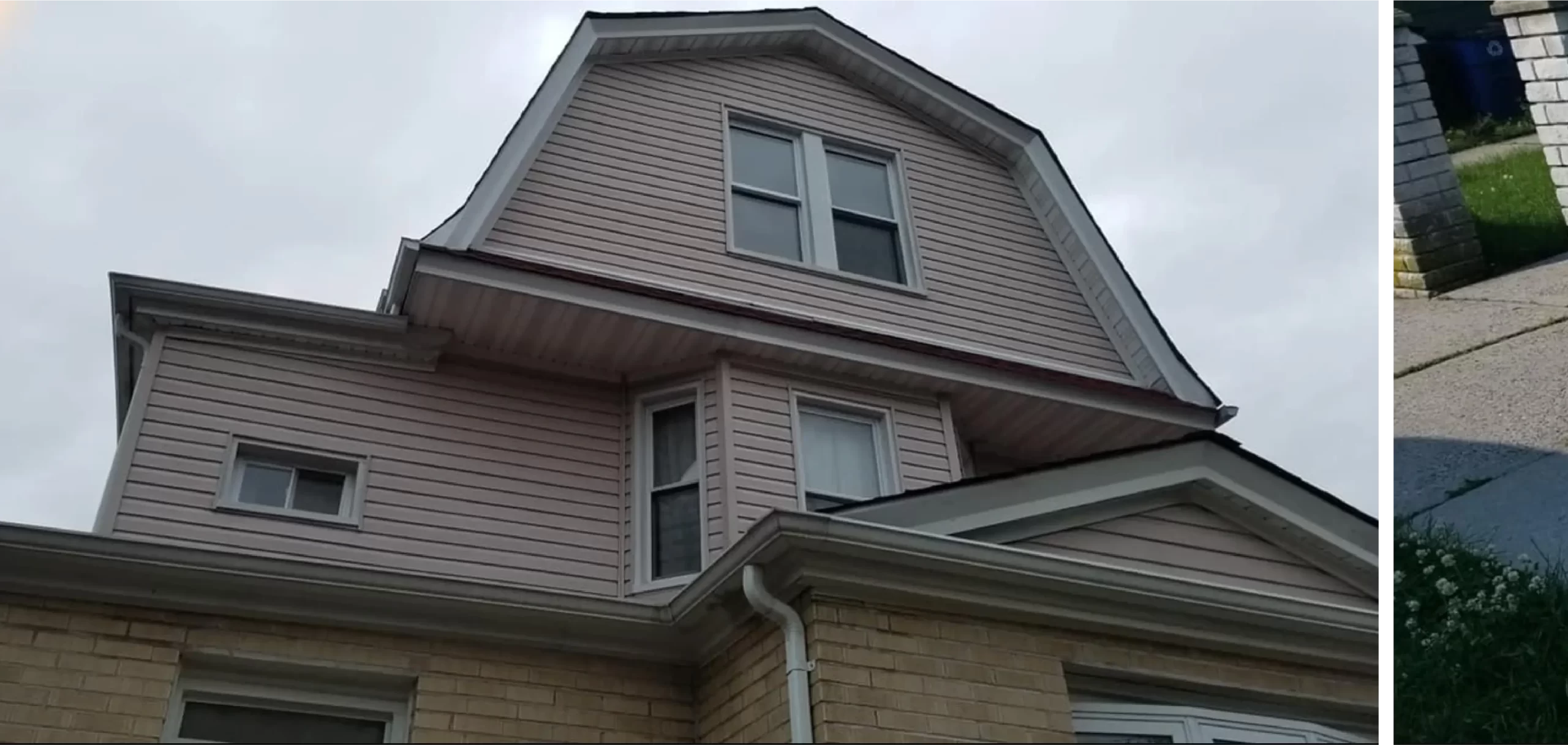 A two-story house with a pinkish upper facade and a lower facade of light yellow bricks. The house features multiple windows and has a white gutter system.